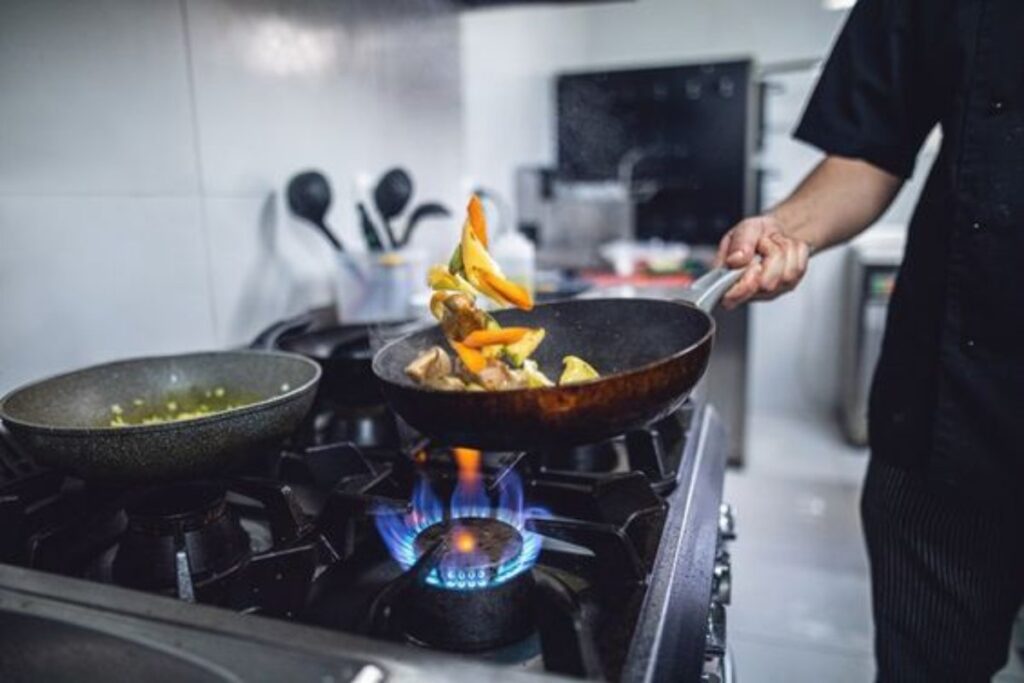 A picture of someone cooking with gas stove