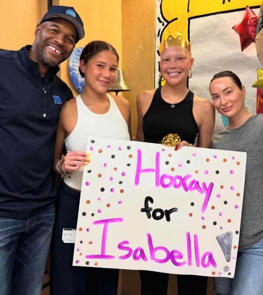 Isabella posing with her family while holding a cardboard celebrating the end of her treatment