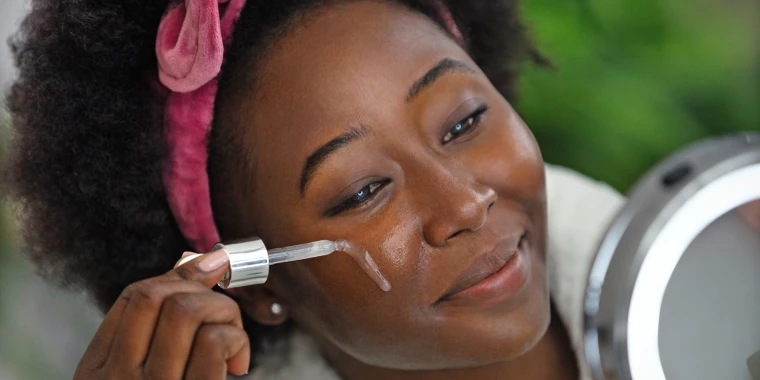 A Picture of a Black Woman Applying Retinol on Her Face