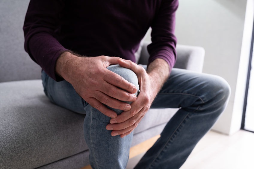 A man holding his aching knee