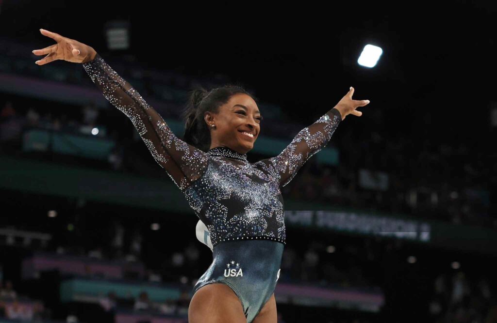 Simone Biles in a leotard posing for the crowd