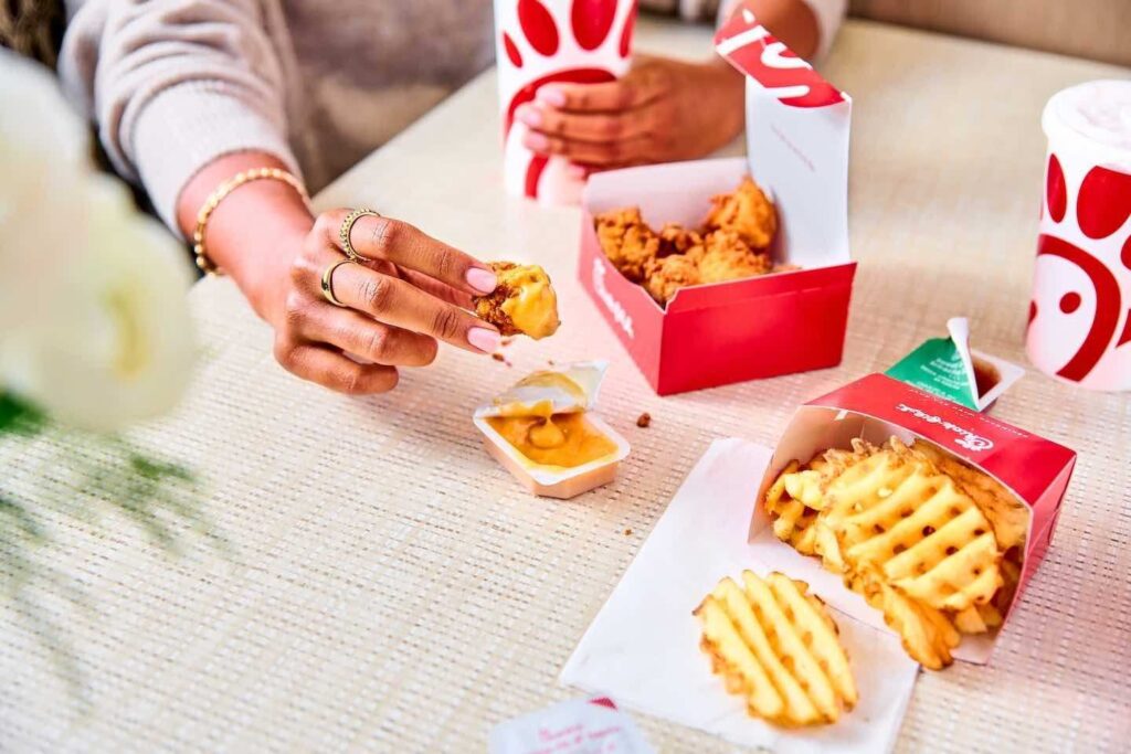 A person seated behind a table loaded with chick-fil-a food items