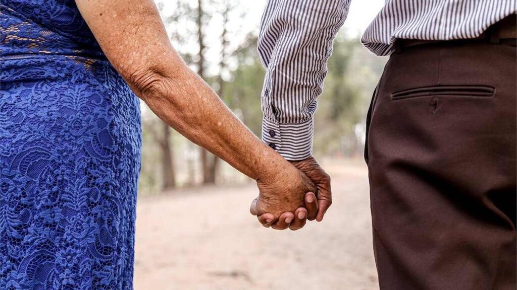 An aged couple walking hand in hand