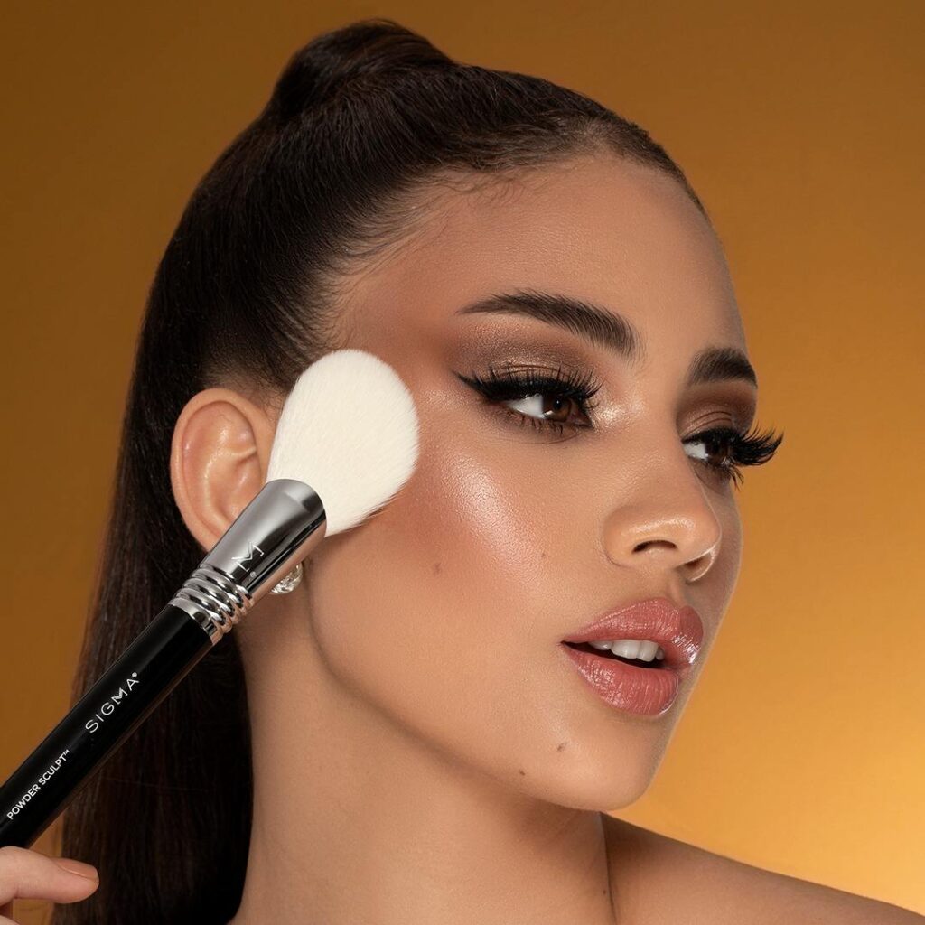 A woman with a brush touching up her makeup