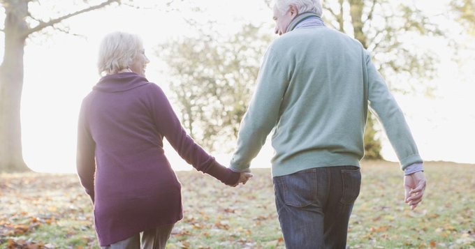 An aged couple walking hand in hand