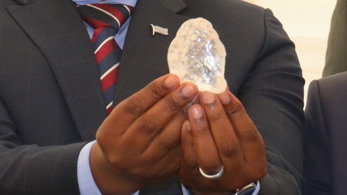 A man in a suit holding up the 2,492-carat Diamond