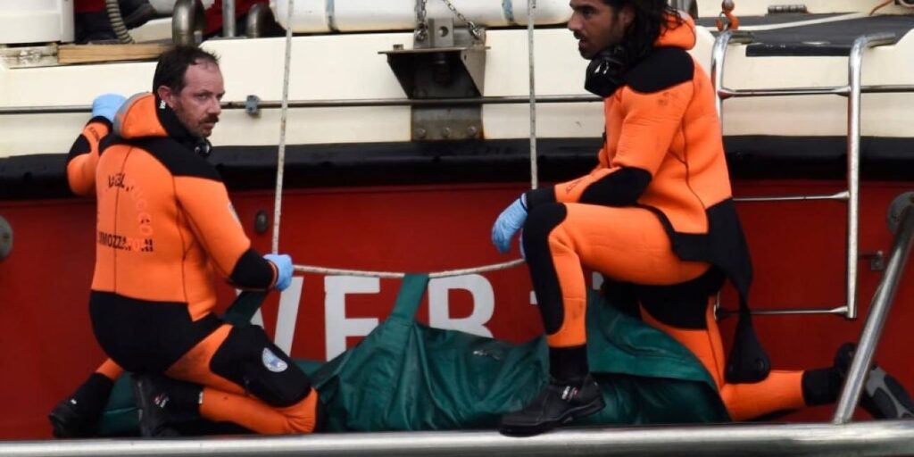 Rescuers with a body they pulled from the sunken Bayesian