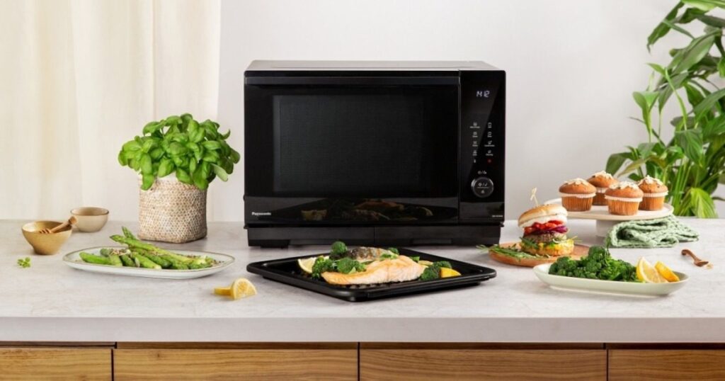 A microwave on a countertop surrounded by food items