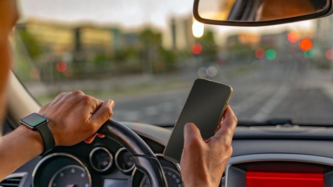 A man driving and using his phone