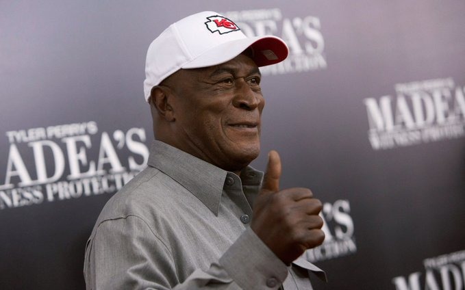 John Amos making the thumbs up sign on a red carpet