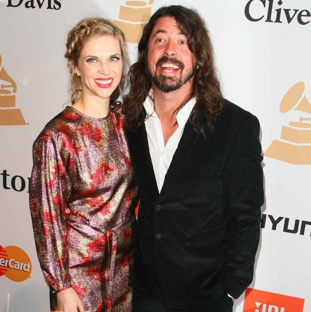 Dave Grohl posing with his wife on a red carpet