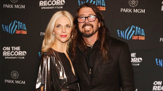 Dave Grohl posing with his wife on a red carpet